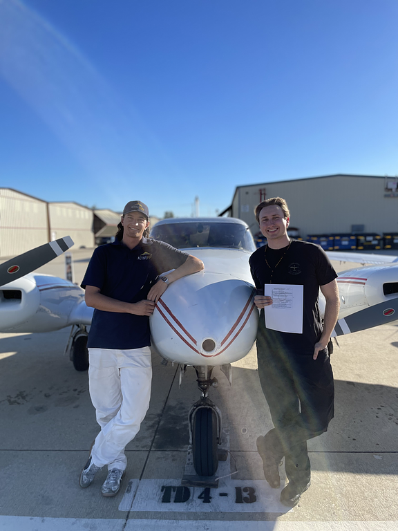 Mitch Rittenhouse with student Quinn holding a multi certificate in front of an aircraft